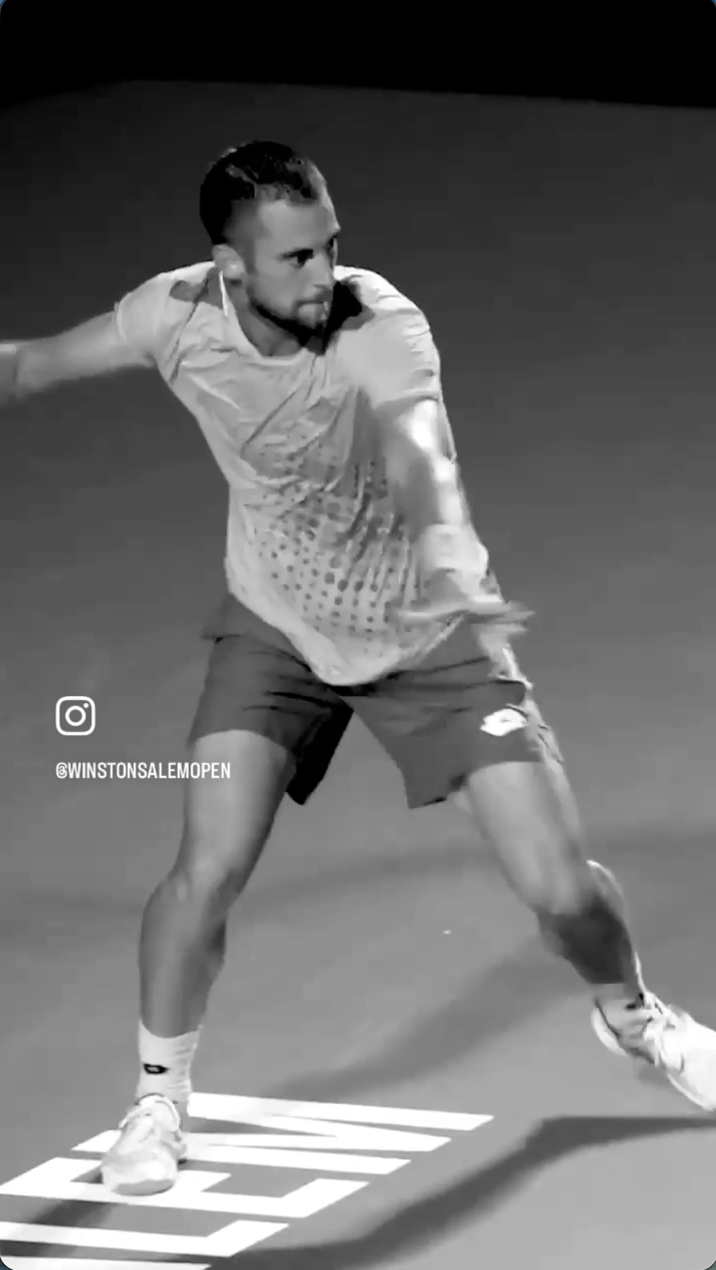 A man swinging a tennis racquet in a black and white video