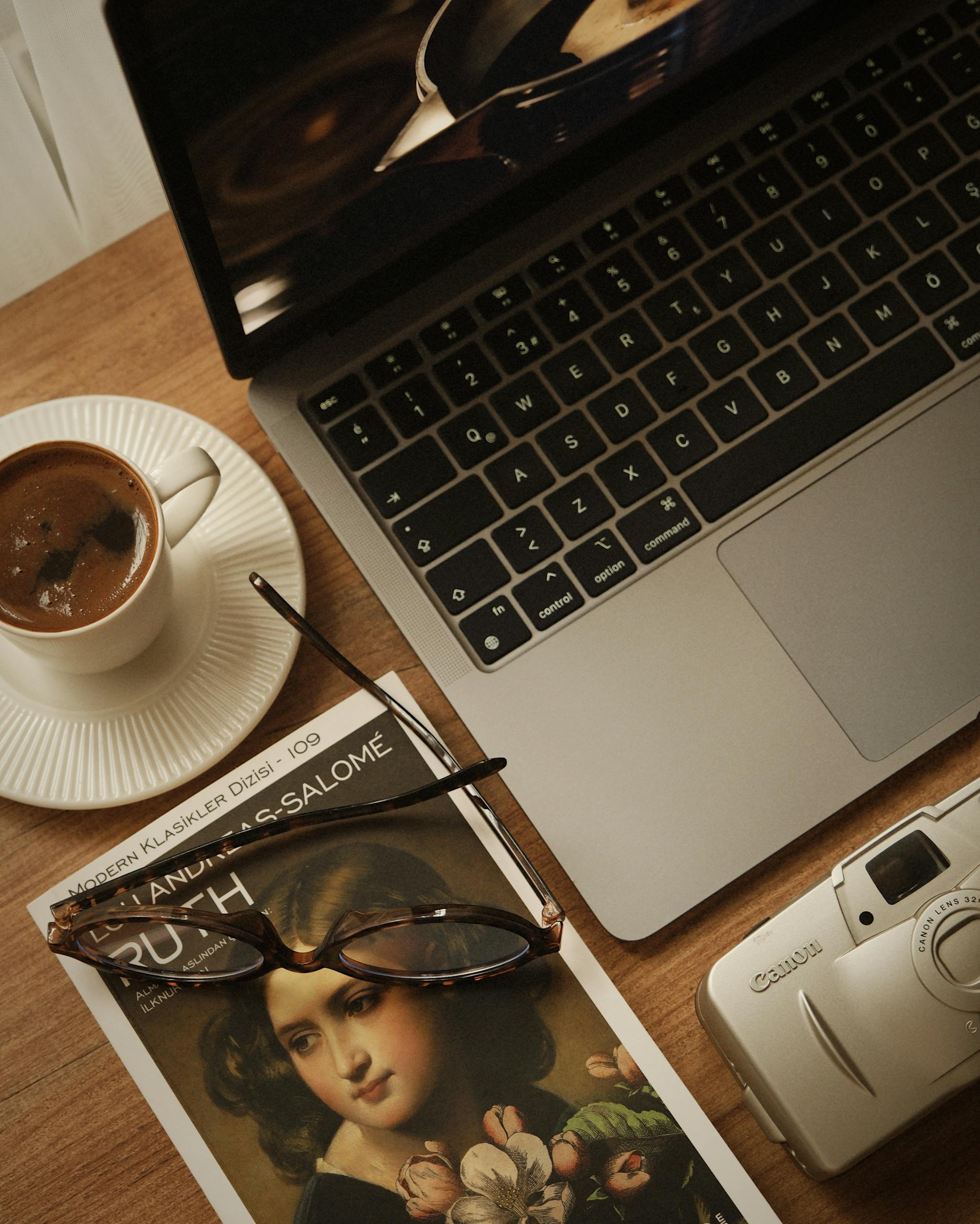 A relaxing setup with coffee, a book, and a laptop on a wooden table.